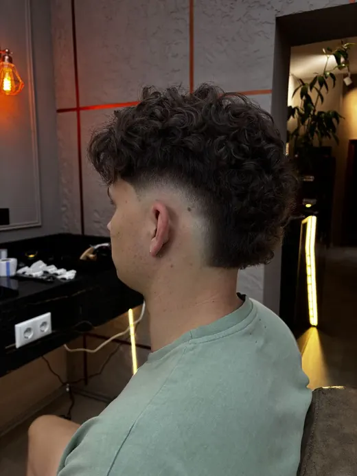 Lockiges Deckhaar mit hohem Fade an den Seiten, von hinten seitlich
