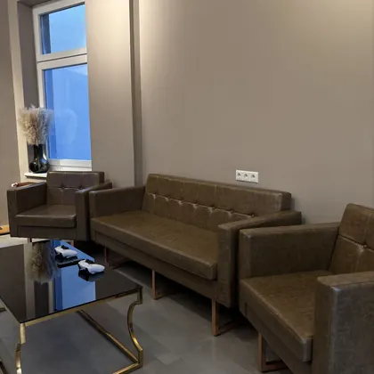 Sitzecke mit Sofa, zwei Sesseln und Glastisch am Fenster